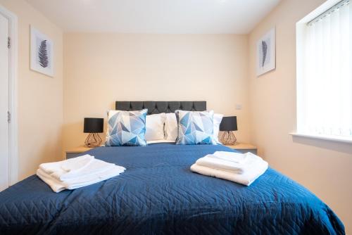 a bedroom with a blue bed with towels on it at Apartment 9 in Worksop