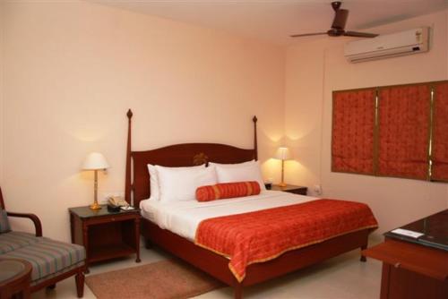 a bedroom with a bed and two lamps and a couch at The Lalit Traveller Khajuraho in Khajurāho