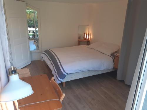 um quarto com uma cama e uma mesa com um candeeiro em Appartement les Acacias em Clamart