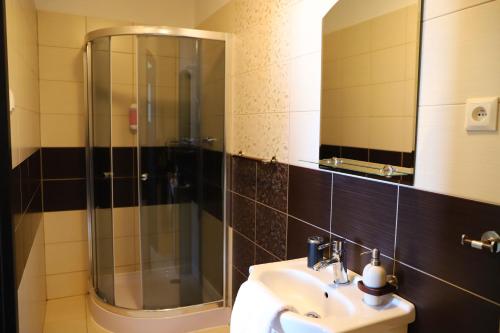ein Bad mit einer Dusche, einem Waschbecken und einem Spiegel in der Unterkunft Hotel Rezident in Turčianske Teplice