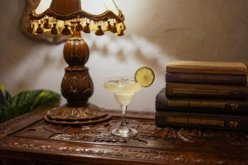 a drink on a table next to a lamp and books at Hotel Vaidila in Alytus
