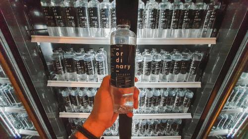 a person holding a bottle in front of a shelf of alcohol at Hotel Ordinary Bangkok in Bangkok