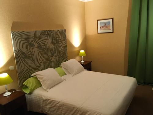 a bedroom with a white bed with a green curtain at Hotel Dorele in Montargis