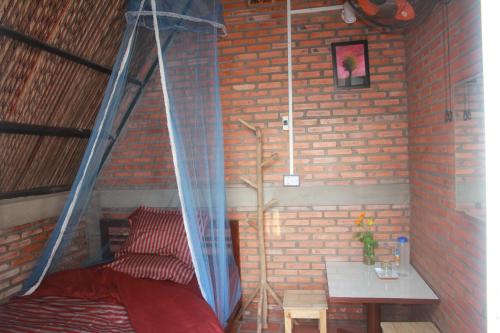 a room with a bed and a table with a curtain at Bầu Bí Mini Farmstay Mekong - Tiền Giang in My Tho