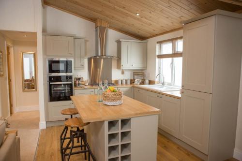 a kitchen with white cabinets and a wooden ceiling at Hollicarrs - Forest Retreat in York