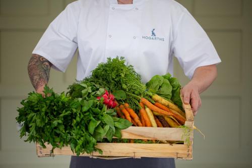 a man holding a crate of carrots and greens at Hogarths in Solihull