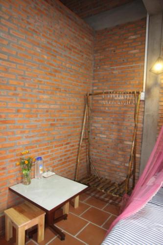 a room with a table and a brick wall at Bầu Bí Mini Farmstay Mekong - Tiền Giang in My Tho