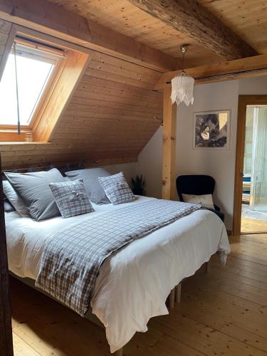 une chambre avec un grand lit avec un plafond en bois dans l'établissement Le Nid de Cigognes, à Hengwiller