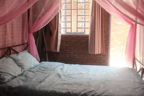 a bedroom with a bed with pink curtains and a window at Bầu Bí Mini Farmstay Mekong - Tiền Giang in My Tho