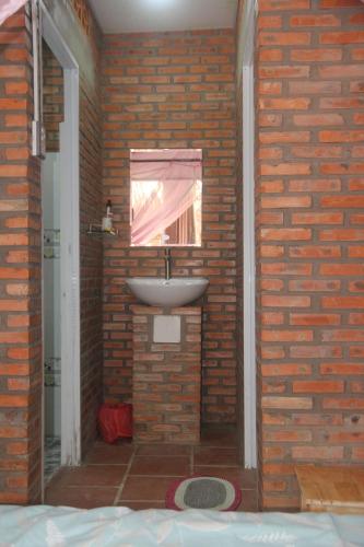 a bathroom with a sink in a brick wall at Bầu Bí Mini Farmstay Mekong - Tiền Giang in My Tho