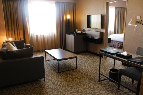 a hotel room with a bed and a living room with a couch at Grand Alora Hotel in Alor Setar