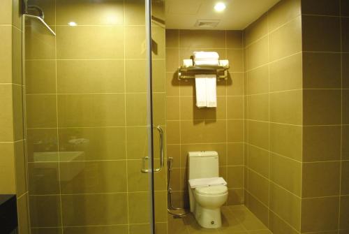a bathroom with a toilet and a glass shower at Grand Alora Hotel in Alor Setar