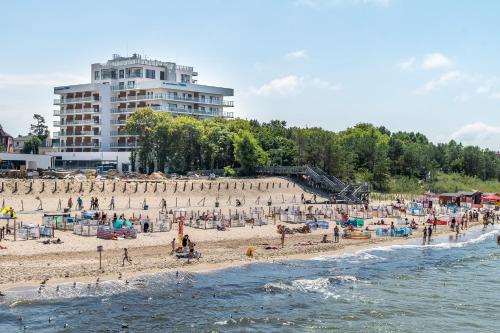 a group of people on a beach near the water at Family Holiday Apartment Aquamarina Prima by Renters in Międzyzdroje