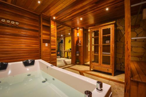 uma banheira num quarto com paredes de madeira em Pousada Borô em Gramado
