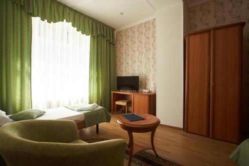 ナリチクにあるSanatoriy Chaikaのベッド、椅子、テーブルが備わるホテルルームです。