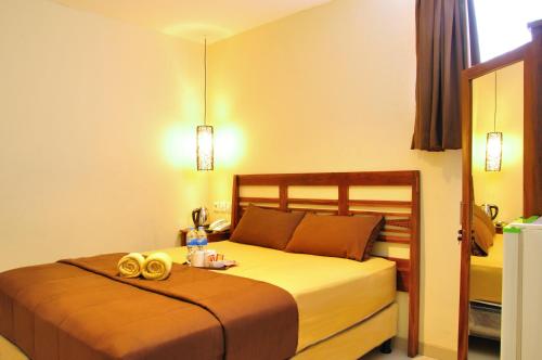una camera d'albergo con un letto con due anelli d'oro di Kuta Sari House a Kuta