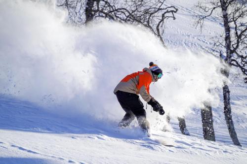 un hombre montando una tabla de snowboard por una pendiente cubierta de nieve en Haukelifjell Skisenter en Vågsli