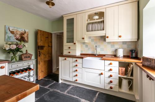 eine Küche mit weißen Schränken und einem Waschbecken in der Unterkunft Maggie Puddle Cottage in Grange Over Sands