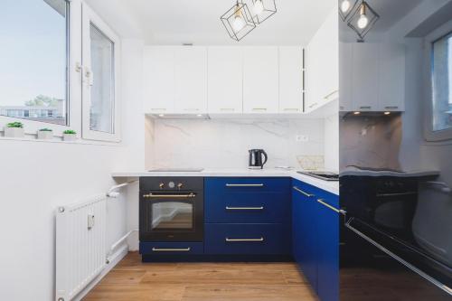 a kitchen with blue cabinets and a black oven at Apartament przy Bulwarach Wiślanych Kościuszki by Renters in Krakow