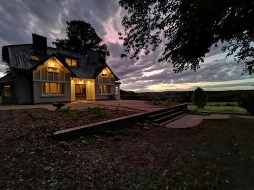 a house with its lights on in the sunset at La Villa du Pré Du Cerf in Spa