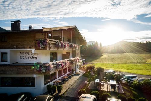 a hotel with cars parked in a parking lot at Landhotel Föhrenhof Ellmau in Ellmau