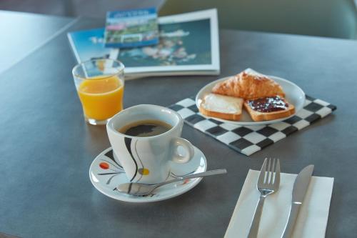 une tasse de café et une assiette de pain et de jus d'orange dans l'établissement Ashley Hotel Le Mans Sud, à Ruaudin