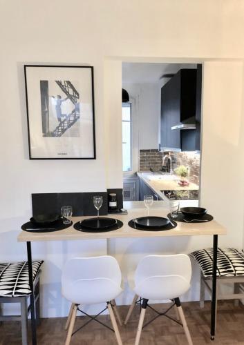 une cuisine avec un comptoir avec quatre chaises et une table dans l'établissement Appartement Pouchard Welkeys, à Saint-Mandé