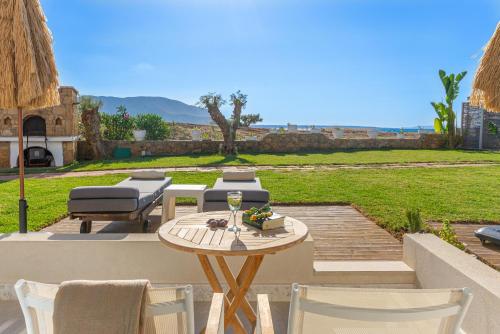 a patio with a table and chairs and a lawn at Pyrgos Blue in Malia