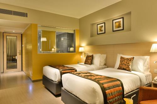 una habitación de hotel con dos camas y un sofá en The Fern Residency, Vadodara, en Vadodara