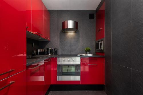 - une cuisine rouge avec des placards rouges et une cuisinière dans l'établissement Królewska 43 by Homeprime, à Varsovie