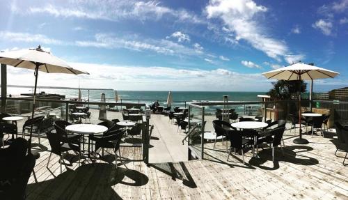 a patio with tables and umbrellas and the ocean at The Addresse on the Beach in Tramore