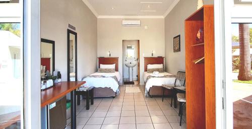 Zimmer mit 2 Betten und einem Schreibtisch in einem Zimmer in der Unterkunft Dive Inn Guesthouse in Pongola
