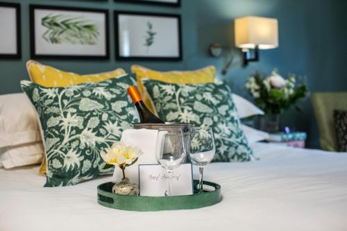 a tray with a bottle of wine and glasses on a bed at Hogarths in Solihull