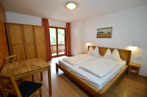 a bedroom with a bed with white sheets and a table at Karlingerhof in Achenkirch