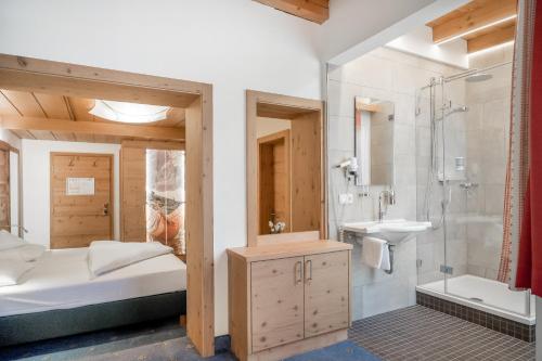 bagno con letto, doccia e lavandino di Das Kaltschmid - Familotel Tirol a Seefeld in Tirol