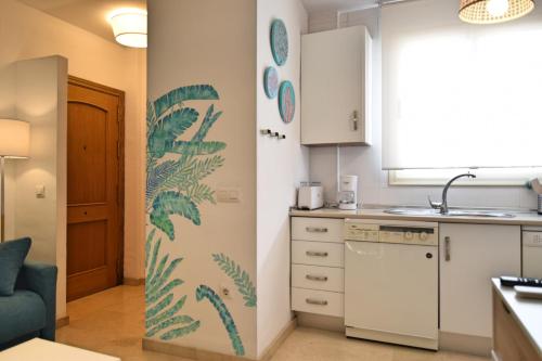 una pequeña cocina con una hoja verde pintada en la pared en Bonito apartamento a 5min.  del centro histórico, en Málaga