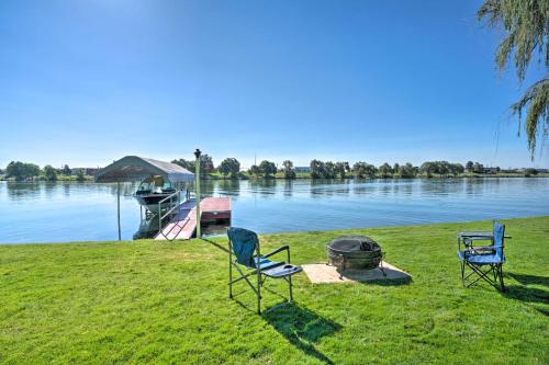 two chairs and a grill next to a boat on a lake at Lake House with Hot Tub - 1 Mi to Surf n Slide in Moses Lake