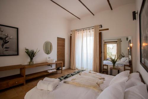 a bedroom with a large white bed and a mirror at Hotel Sin Nombre in Oaxaca City