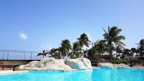 a swimming pool with rocks in the water with palm trees at Studio Paradis 3* in Saint-François