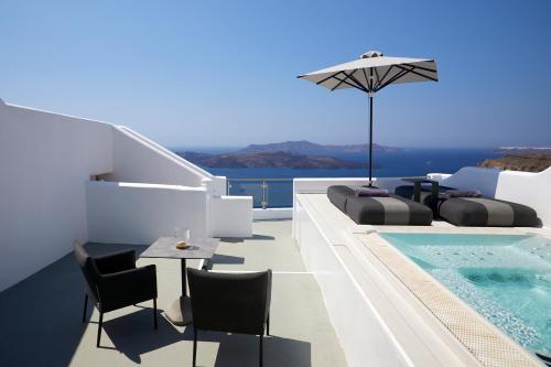 a villa with a pool and a table and chairs at Petit Palace Suites in Fira