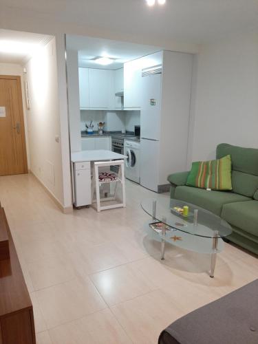 a living room with a green couch and a table at Apartamento Barbanza con plaza de garaje in Porto do Son