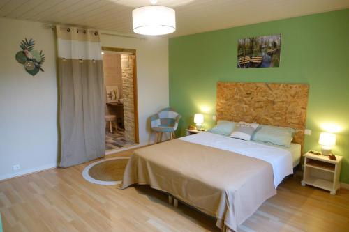 um quarto com uma cama grande e paredes verdes em AU COEUR DU MARAIS em Saint-Hilaire-la-Palud