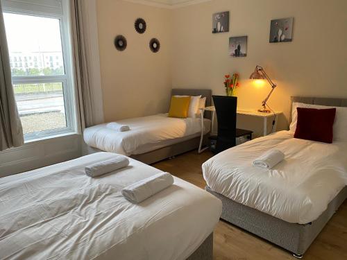 a room with two beds and a desk and a window at Serviced Property Apartment 1 in Plymouth
