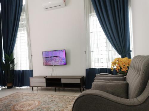 sala de estar con cortinas azules y TV en Damai Homestay Alor Setar en Alor Setar