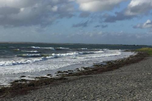 a sandy beach with waves in the ocean at Tigh Noor - Escape to Kinvara by the sea! in Galway