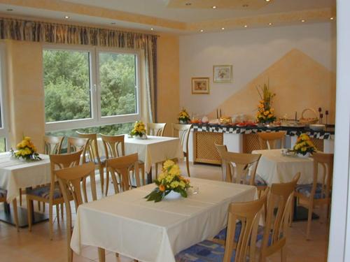 un restaurant avec des tables blanches, des chaises et des fleurs. dans l'établissement Hotel Pit Lane "Home of Motorsport", à Nürburg
