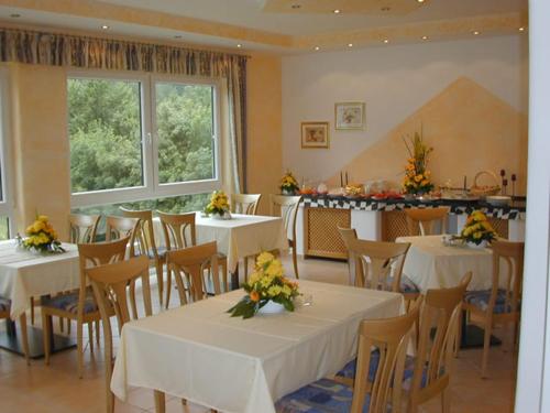 a restaurant with white tables and chairs with flowers on them at Hotel Pit Lane "Home of Motorsport" in Nürburg