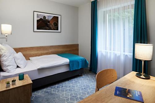 a hotel room with a bed and a table at Hotel Adalbert Szent Tamás ház in Esztergom