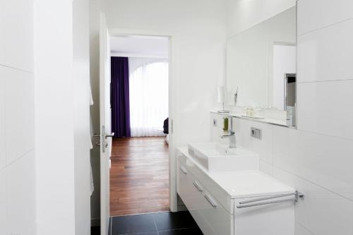 a white bathroom with two sinks and a mirror at Central Hotel in Villingen-Schwenningen