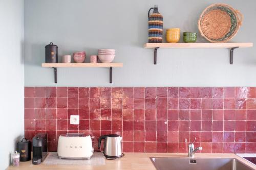 uma cozinha com azulejos vermelhos na parede e um lavatório em Fabulous studio in Châtelain area with balcony em Bruxelas